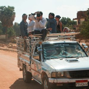 A group of travelers enjoy a ride on a truck in Luxor, Egypt under a clear sky.