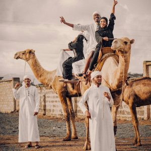 Group enjoying a joyful camel ride in a Middle Eastern setting with traditional attire.